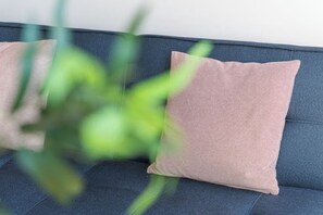 A sofa with a textured cushion and a plant in the foreground. - Candy Crush: A Cozy Apartment in the Heart of Porto (Porto)
