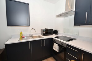 A compact kitchen with a sink, a microwave, and a stove. - Modern Studio Apartment in Central Bradford (Bradford)