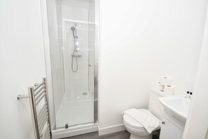 A modern bathroom with a glass-enclosed shower, a toilet, and a sink. - Modern Studio Apartment in Central Bradford (Bradford)