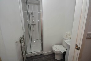 A bathroom with a glass-enclosed shower, a toilet, and a towel rack. - Modern Studio Apartment in Central Bradford (Bradford)