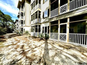 A multi-story hotel with balconies, a covered outdoor area, and a dirt ground. - New Owner - 3BR 2 bath first floor corner condo just a short walk to the beach! (Santa Rosa Beach)