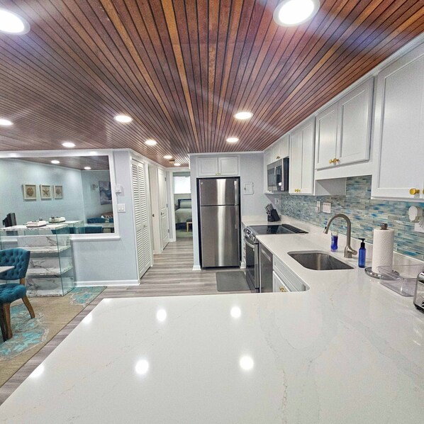 A modern kitchen with a central island, stainless steel appliances, and a wooden ceiling. - Enjoy beautiful oceanfront views of the Ocean City coastline in this one bedroom, one bath condo located just a few steps from the beach! (Ocean City)