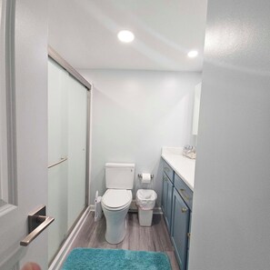 A compact bathroom with a toilet, a trash bin, and a sink with a mirror above it. - Enjoy beautiful oceanfront views of the Ocean City coastline in this one bedroom, one bath condo located just a few steps from the beach! (Ocean City)