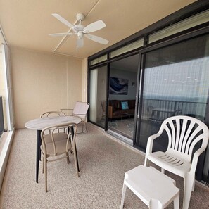 A balcony with a table and chairs, a ceiling fan, and a sliding glass door leading to an interior space. - Enjoy beautiful oceanfront views of the Ocean City coastline in this one bedroom, one bath condo located just a few steps from the beach! (Ocean City)
