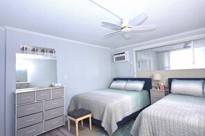 A bedroom with two beds, a dresser, a ceiling fan, and an air conditioning unit. - Enjoy beautiful oceanfront views of the Ocean City coastline in this one bedroom, one bath condo located just a few steps from the beach! (Ocean City)