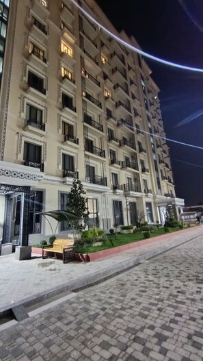 A multi-story hotel with balconies, a paved walkway, and a small seating area. - Spacious and bright apartment in the Uzbegim RC, Tashkent. (Тоshkent)