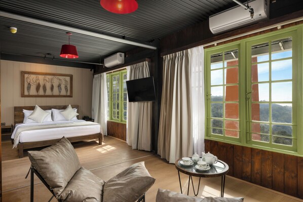 A hotel room with a bed, a sofa, a TV, a window with curtains, and a table with tea set. - Newburgh Ella - The Tea Factory Resort (Ella)