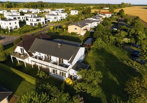 Een woonwijk met moderne huizen, een groot huis met balkon, en een verzorgd gazon.