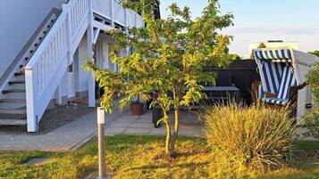 Un quartier résidentiel avec un escalier blanc, un petit arbre et une chaise à rayures.