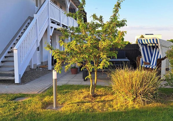 A residential area with a white staircase, a small tree, and a striped chair.