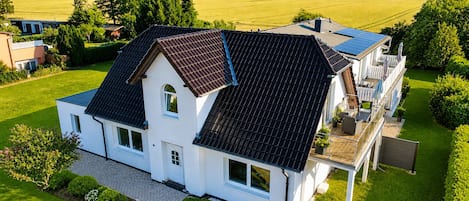 A two-story house with a sloped roof, a balcony, and a well-maintained lawn.