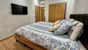 A bedroom with a bed, a flat-screen TV mounted on the wall, and a wardrobe. - Bel Appartement en Résidence et Piscine (Marrakech)