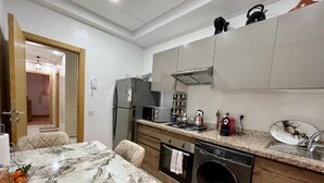 A modern kitchen with a marble countertop, stainless steel appliances, and a built-in oven. - Bel Appartement en Résidence et Piscine (Marrakech)