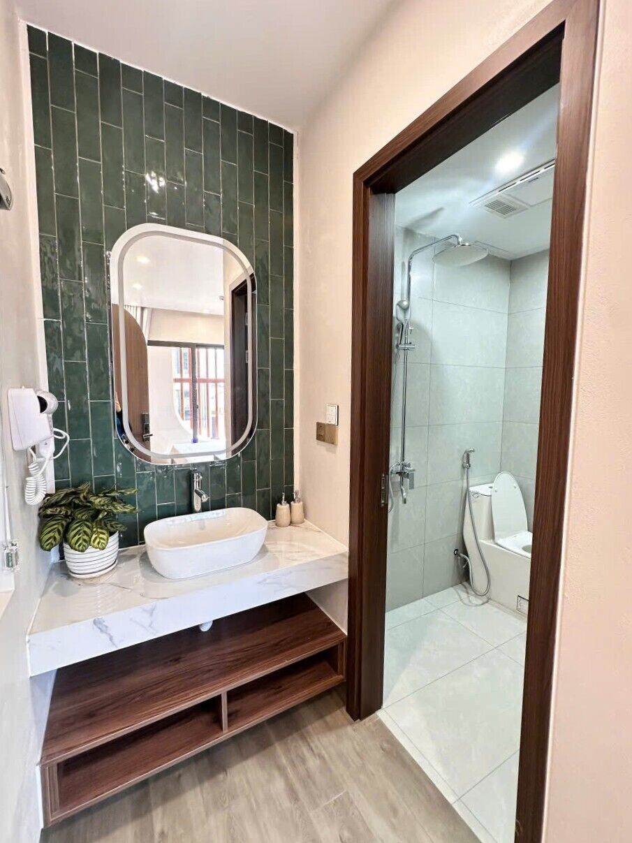 A modern bathroom with a white sink, a large mirror, and a shower area.
