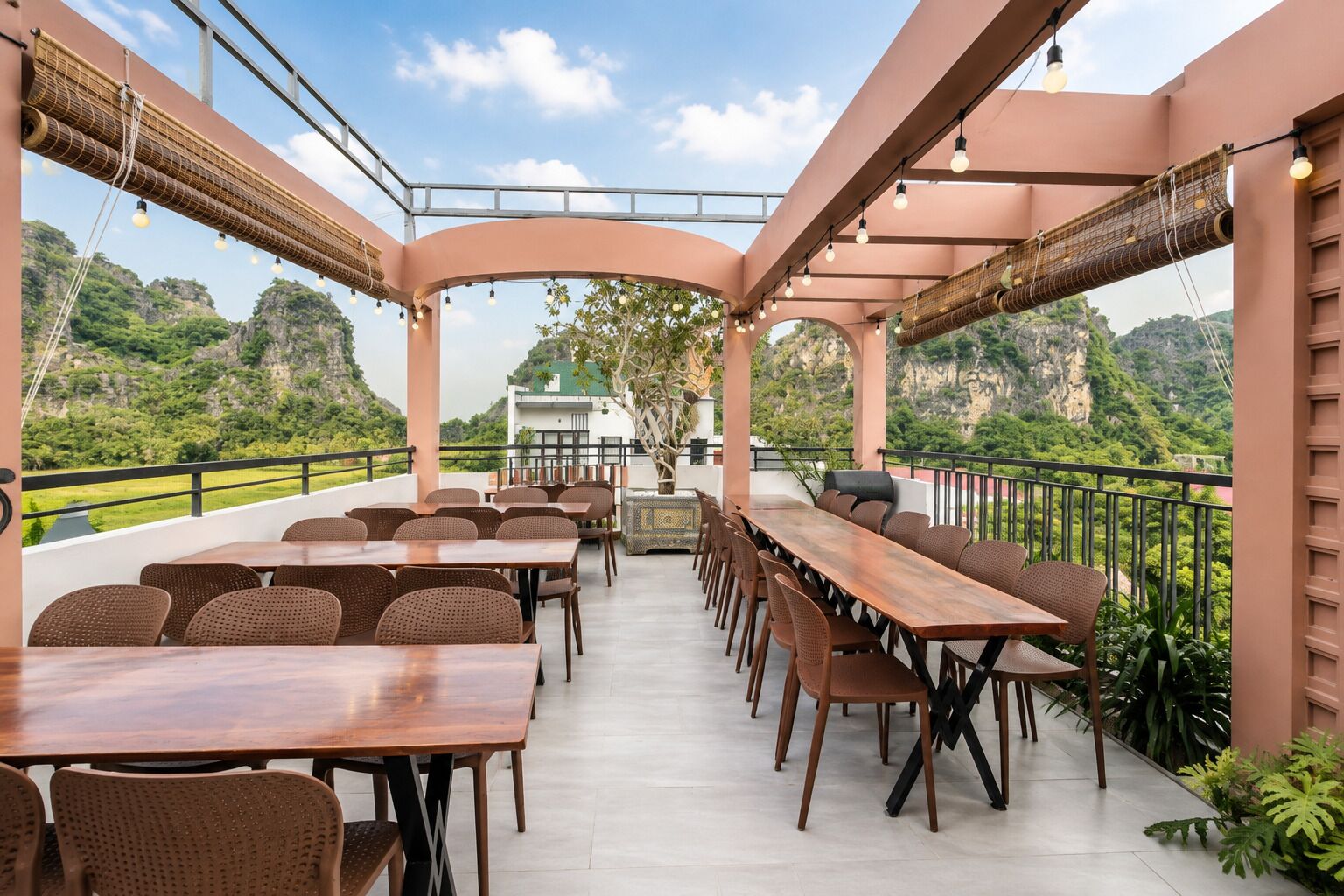 An outdoor dining area with tables and chairs, overlooking a mountainous landscape.