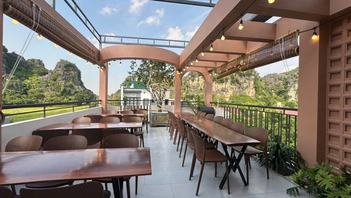An outdoor dining area with tables and chairs, a covered walkway, and a view of the surrounding landscape.
