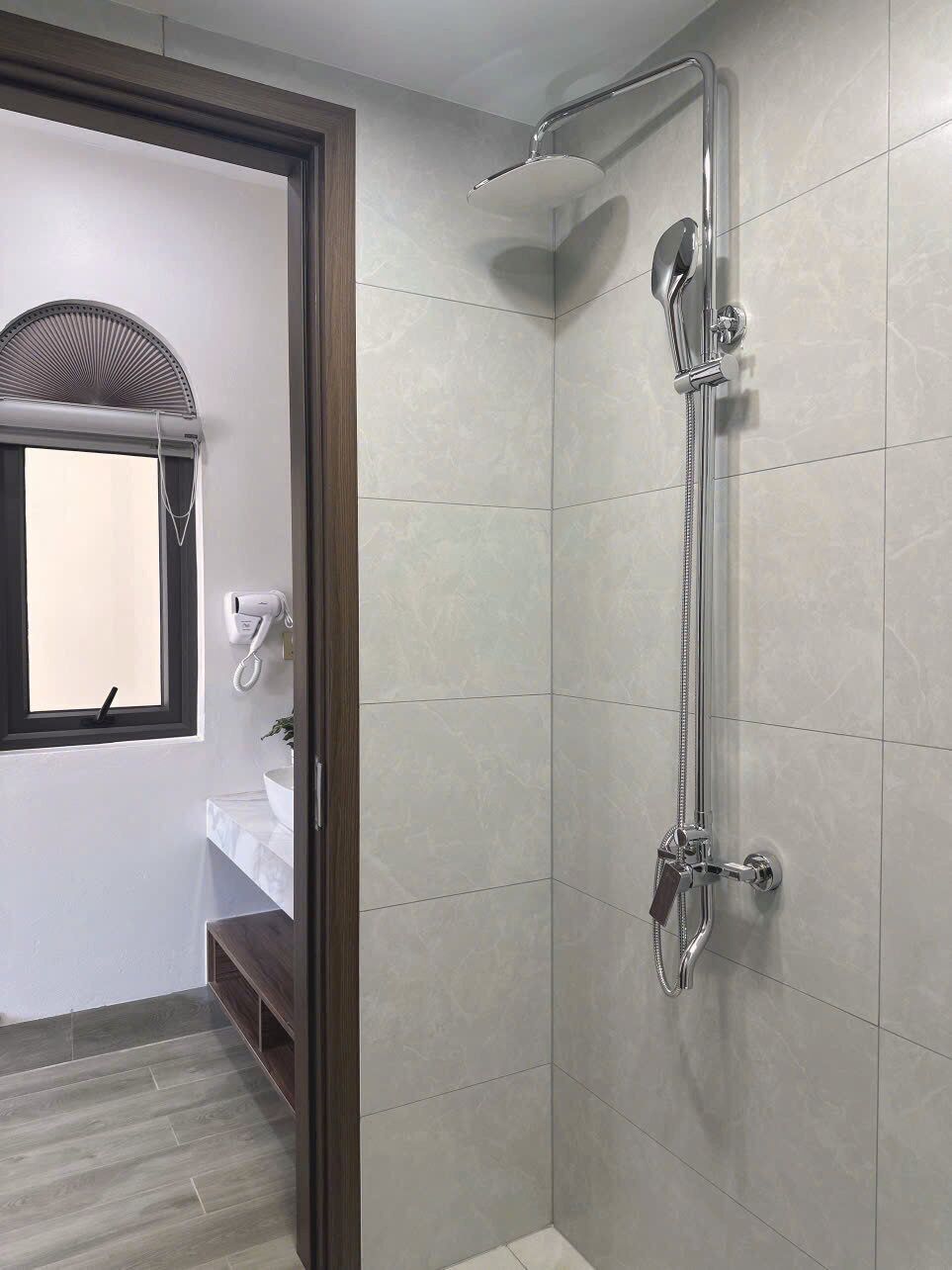 Un baño con ducha, ventana y lavamanos.