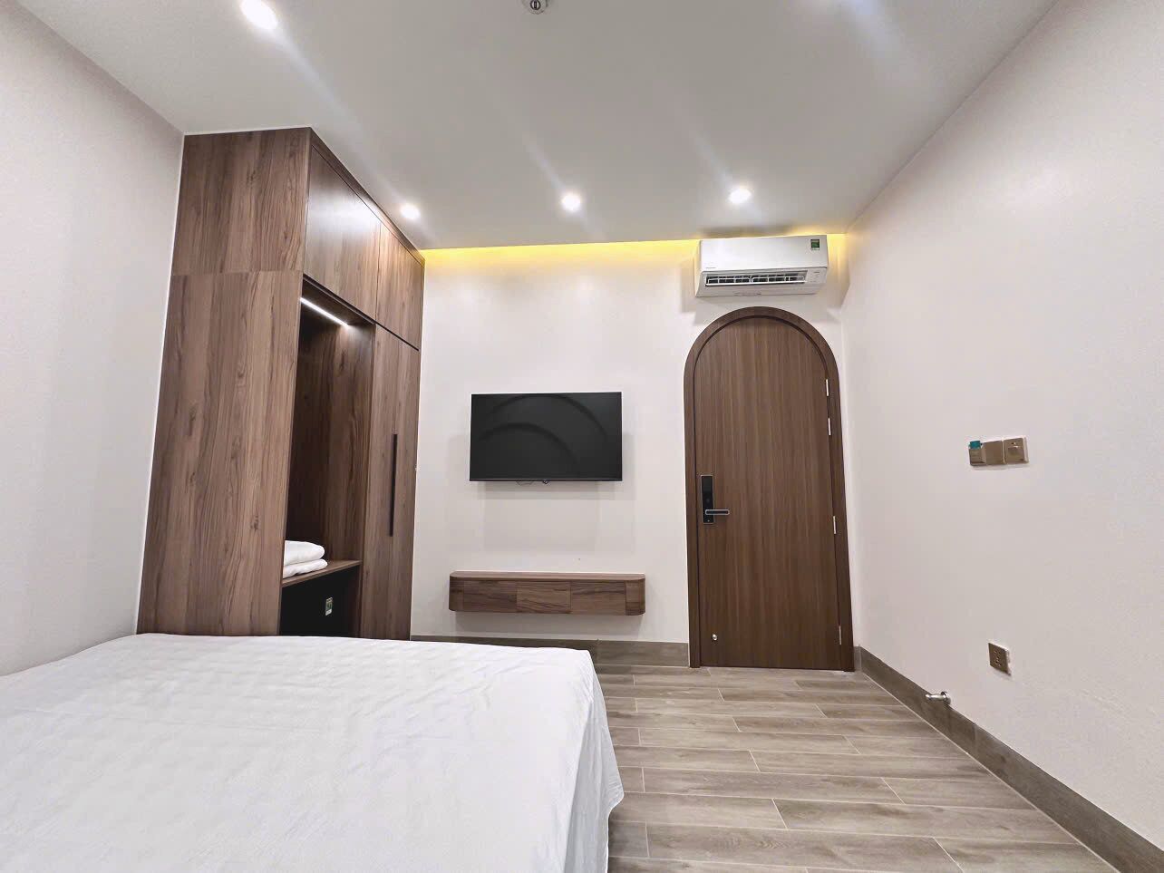 Una camera da letto con un letto, un armadio, una TV a parete e una porta.