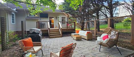 A patio area with outdoor furniture, a covered seating area, and a house in the background.