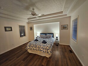 A bedroom with a bed, ceiling fan, and two bedside tables with lamps.