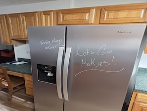 Un réfrigérateur Whirlpool en acier inoxydable, avec des notes manuscrites collées sur la porte.