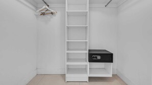 A white closet with multiple shelves and a black storage unit. - Oceanview Highrise - Amenities (Hollywood)