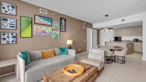 A modern living room with a sofa, coffee table, and artwork on the wall. - Oceanview Highrise - Amenities (Hollywood)