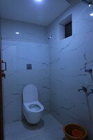 Un baño con inodoro, ducha y una ventana pequeña.