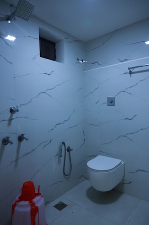 Un baño con inodoro blanco, zona de ducha e lavamanos.
