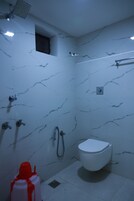 A bathroom with a white toilet, a shower area, and a sink.
