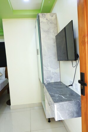 Una habitación con una cama, un televisor montado en la pared y un mueble con diseño de mármol.