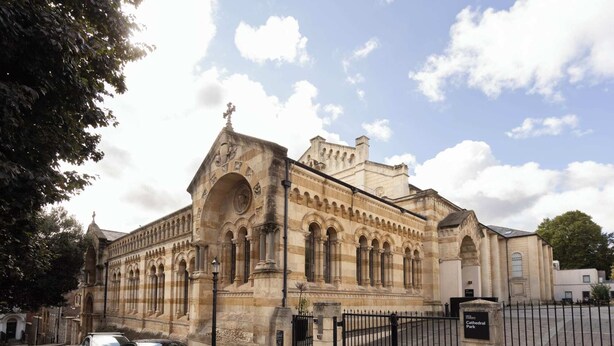 A historic building with a large arched entrance, a clock tower, and a gated driveway. - Student Only Cathedral Park (Bristol)