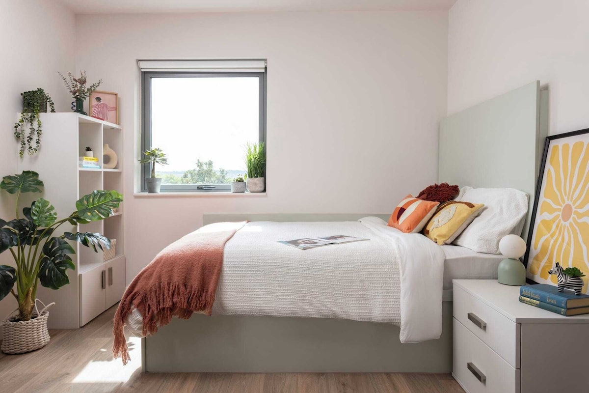 A bedroom with a bed, bedside table, and a window.