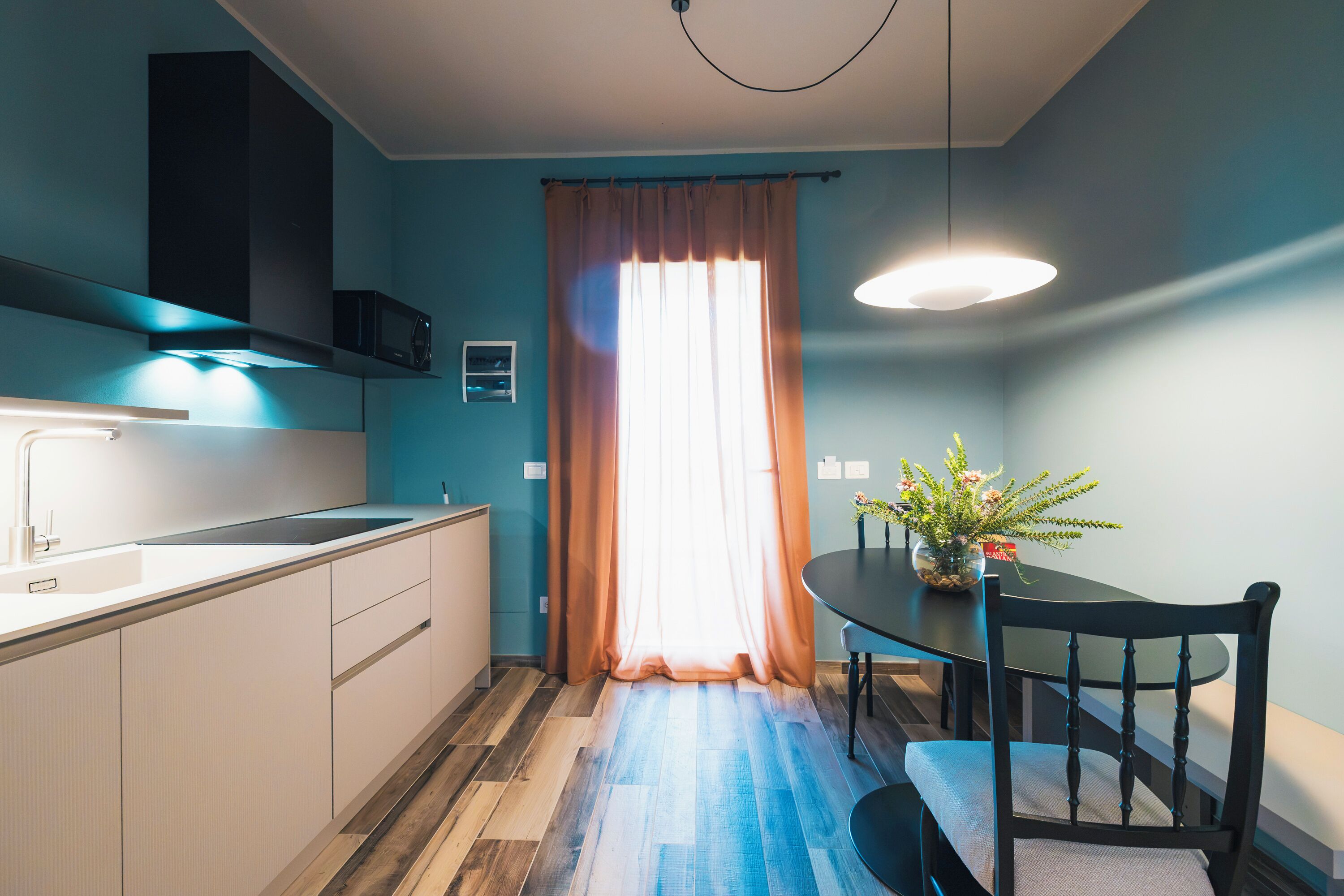 A modern kitchen with a built-in microwave, a sink, and a dining area with a table and chairs.