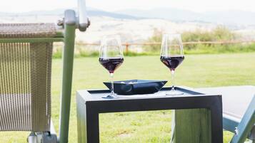 Zwei Gläser Rotwein auf einem quadratischen Tisch mit Blick auf die Landschaft.