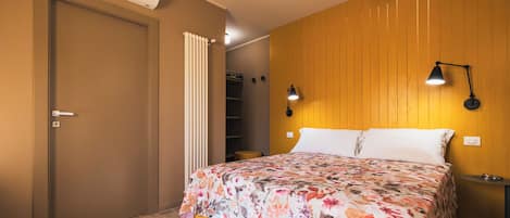 A bedroom with a bed, a bedside lamp, a radiator, and a wardrobe.
