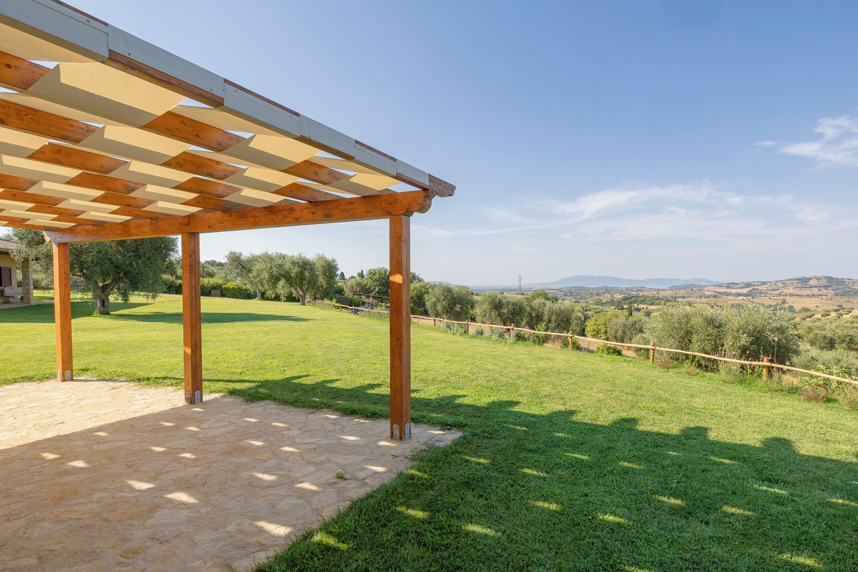 Un espace extérieur abrité offrant une vue sur un paysage verdoyant et des collines lointaines.