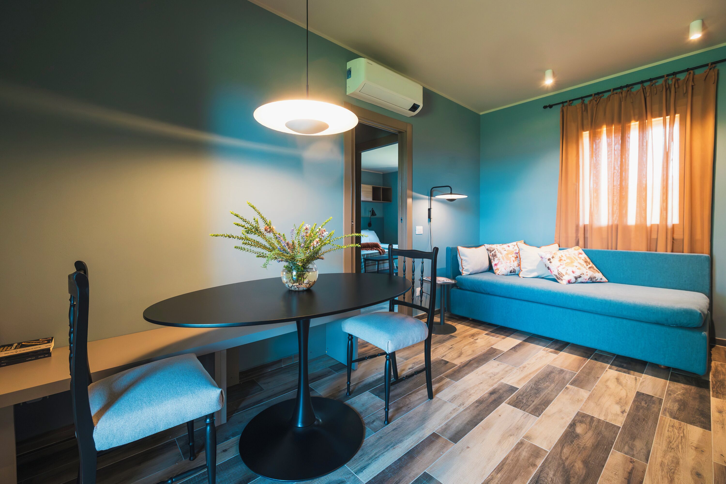 A modern living room with a dining table, sofa, and a blue wall.