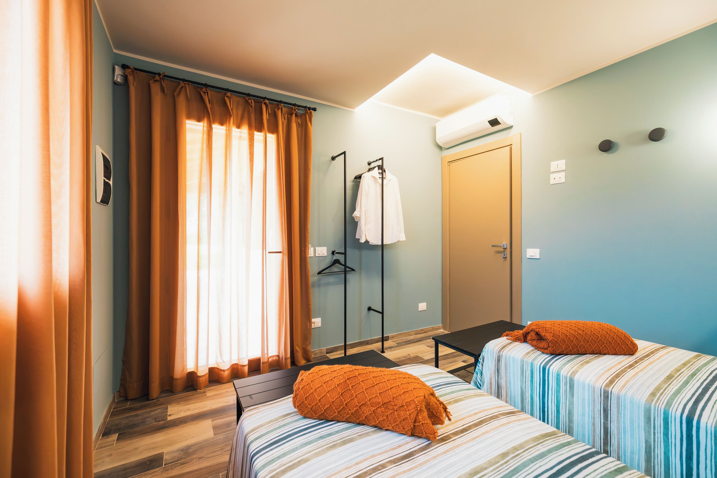 A hotel room with two beds, a bathroom, and a window with curtains.