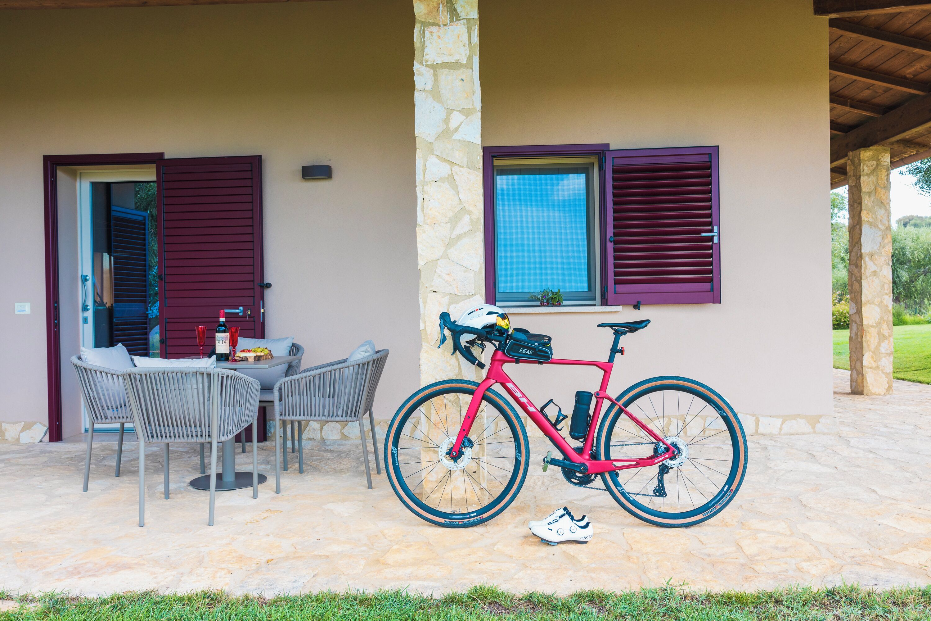 An outdoor patio with a table and chairs, a red bicycle, and a stone wall.