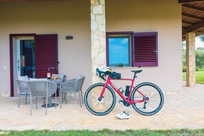 Eine Terrasse im Freien mit Tisch und Stühlen, einem roten Fahrrad und einer Steinmauer.