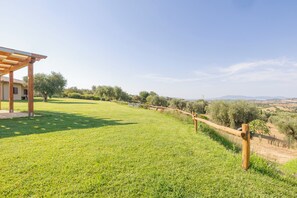 Ein grünes, offenes Gelände mit einer Holzpergola und Blick auf die Landschaft.