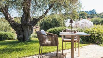Un espace extérieur aménagé avec une table et des chaises, une lampe et un grand arbre.