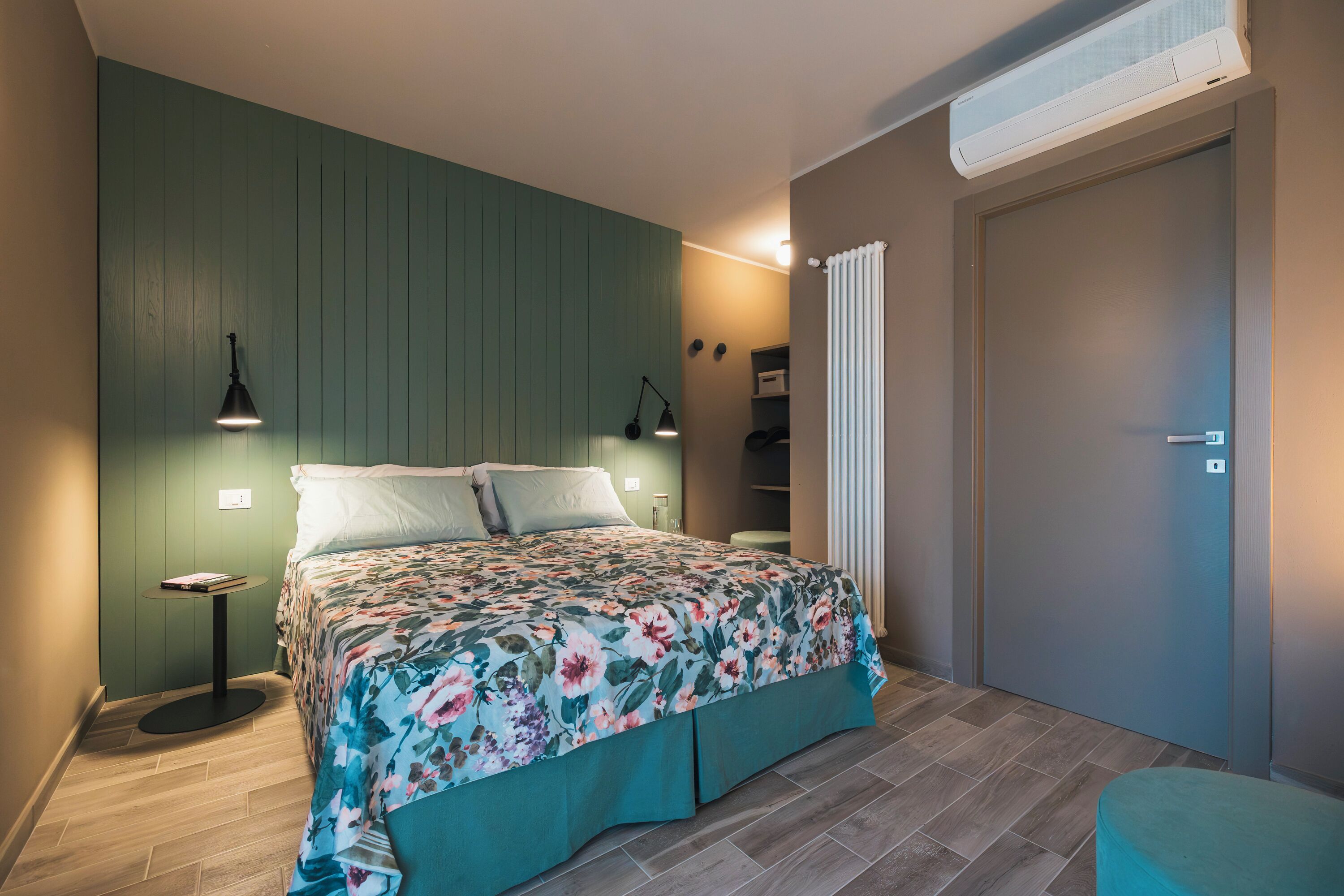Un dormitorio con cama, lámparas de noche, un radiador y una puerta.