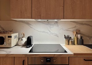 A kitchen with a built-in stove, a kettle, a microwave, and wooden cabinets. - Le Pavot Perché Terrace - Air-Conditioned - Wi-Fi - Downtown (Avignon)