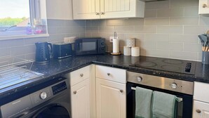 Een moderne keuken met een vaatwasser, magnetron, fornuis en oven.