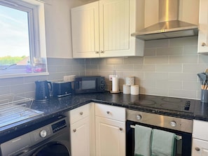 A modern kitchen with a dishwasher, microwave, stove, and oven. - 2-Bed Milton Keynes Maisonette Parking (Milton Keynes)