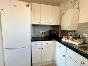 Eine Küche mit weißen Schränken, einer schwarzen Arbeitsplatte, einem Toaster und einem Spülbecken.