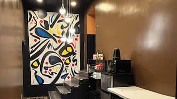 A modern kitchen with a wooden floor, a black countertop, and a colorful abstract wall art.