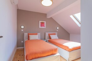 A bedroom with two beds, a skylight, and a framed picture on the wall. - Golden Hour | Luxury 4-Bedroom Home for Families & Groups (Porto)
